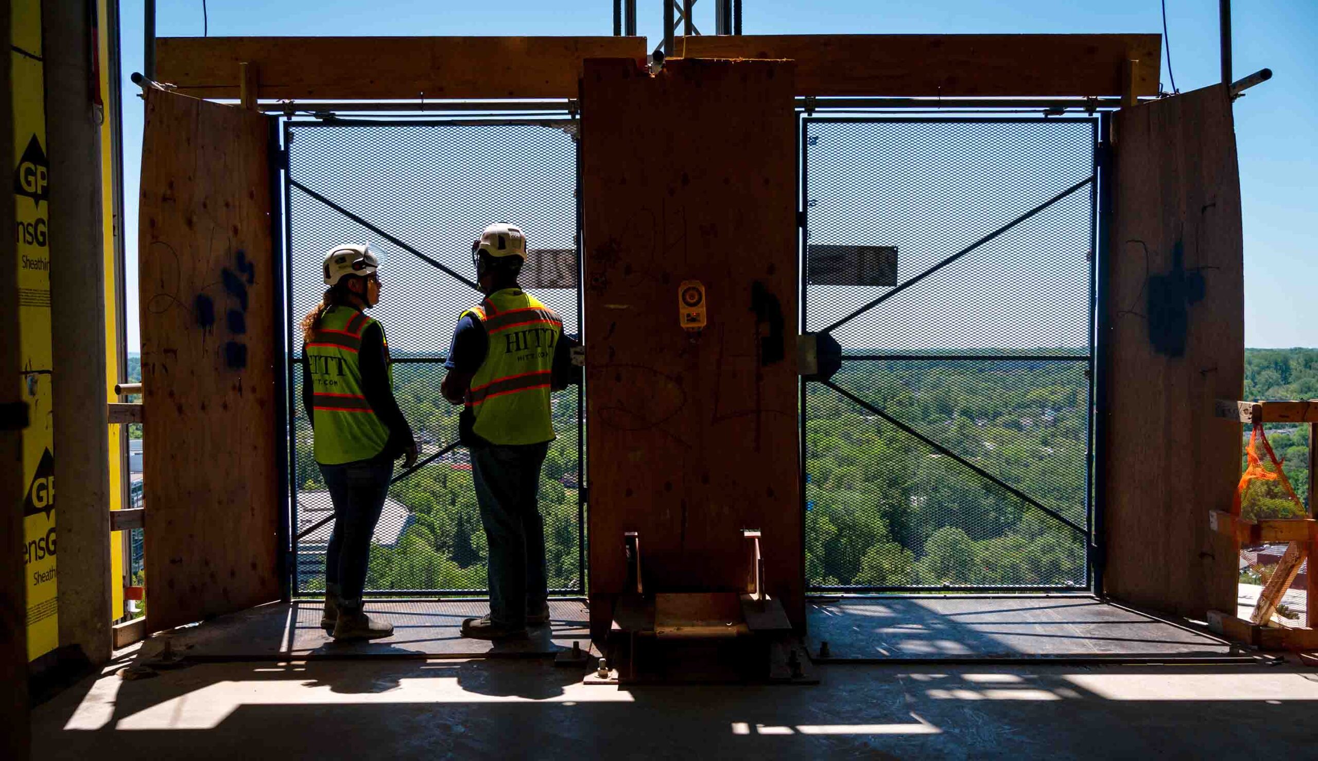 two construction workers looking outside of a building under construction